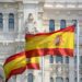 Primer plano de banderas de España ondeando al viento frente a un edificio emblemático de Madrid, simbolizando el impulso nacional al nuevo Plan de Derechos Culturales.