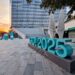 Escultura urbana con el logotipo “GO! 2025” en Gorizia, Italia, anunciando su designación como Capital Europea de la Cultura, con edificios modernos y atardecer de fondo.