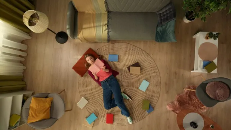 Mujer leyendo rodeada de libros en casa, representando novelas sobre crisis climática y resiliencia con esperanza