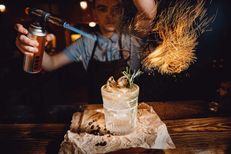 Bartender prepara un cóctel con fuego y especias, reflejando la coctelería en Nepal con innovación artesanal y bares reconocidos internacionalmente.