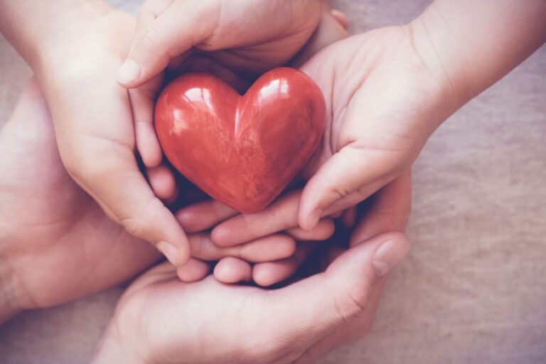 Manos sosteniendo un corazón rojo simbolizan unión, solidaridad y el impacto del nuevo centro recreativo en Paterson Nueva Jersey.