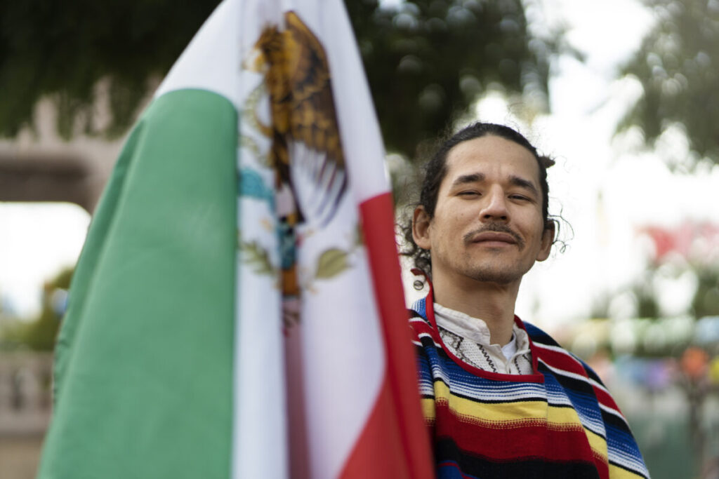 Persona migrante en Estados Unidos sosteniendo una bandera de México