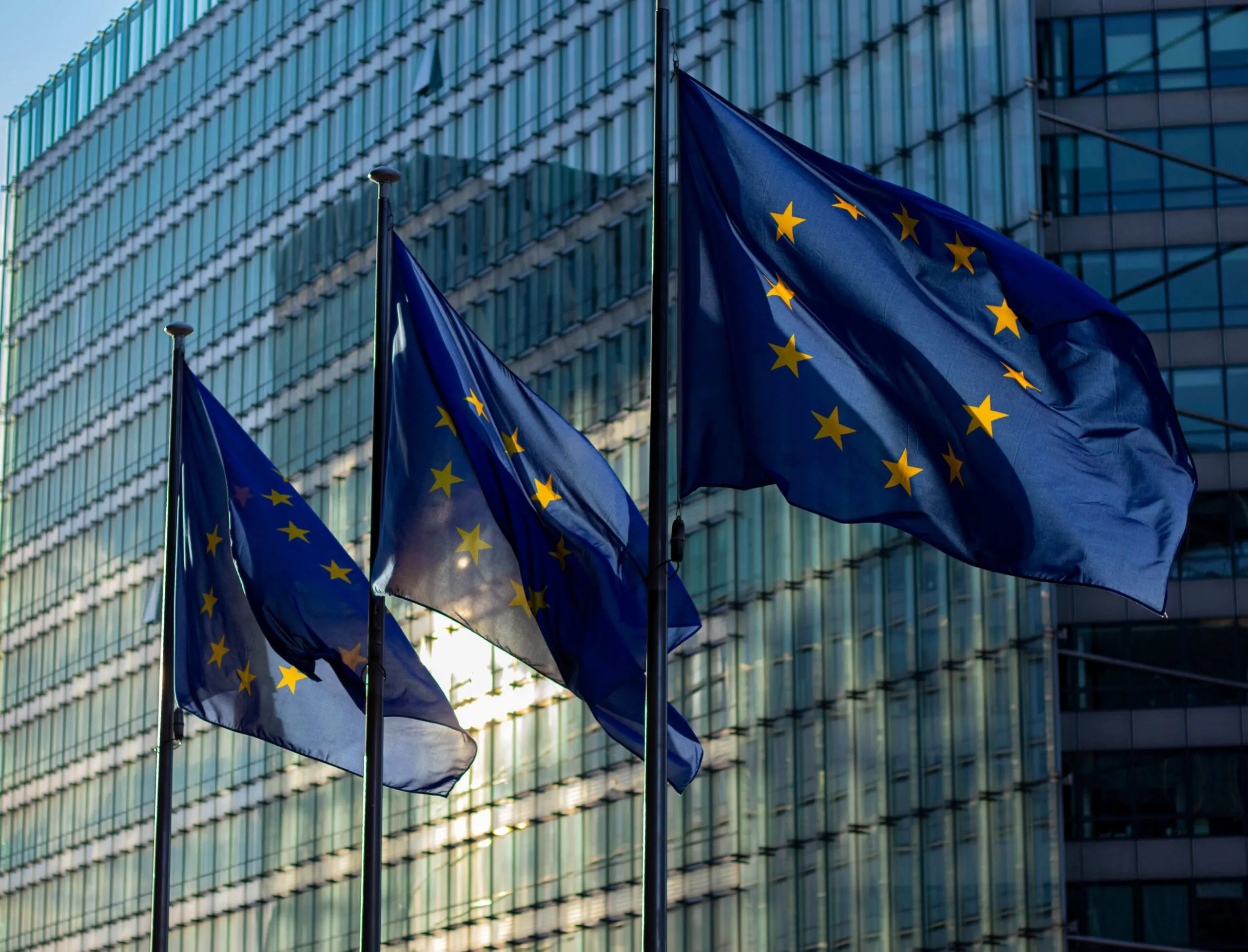 Banderas de la Unión Europea ondean frente a un edificio institucional, representando el compromiso europeo con la cultura, el patrimonio y la cooperación internacional.
